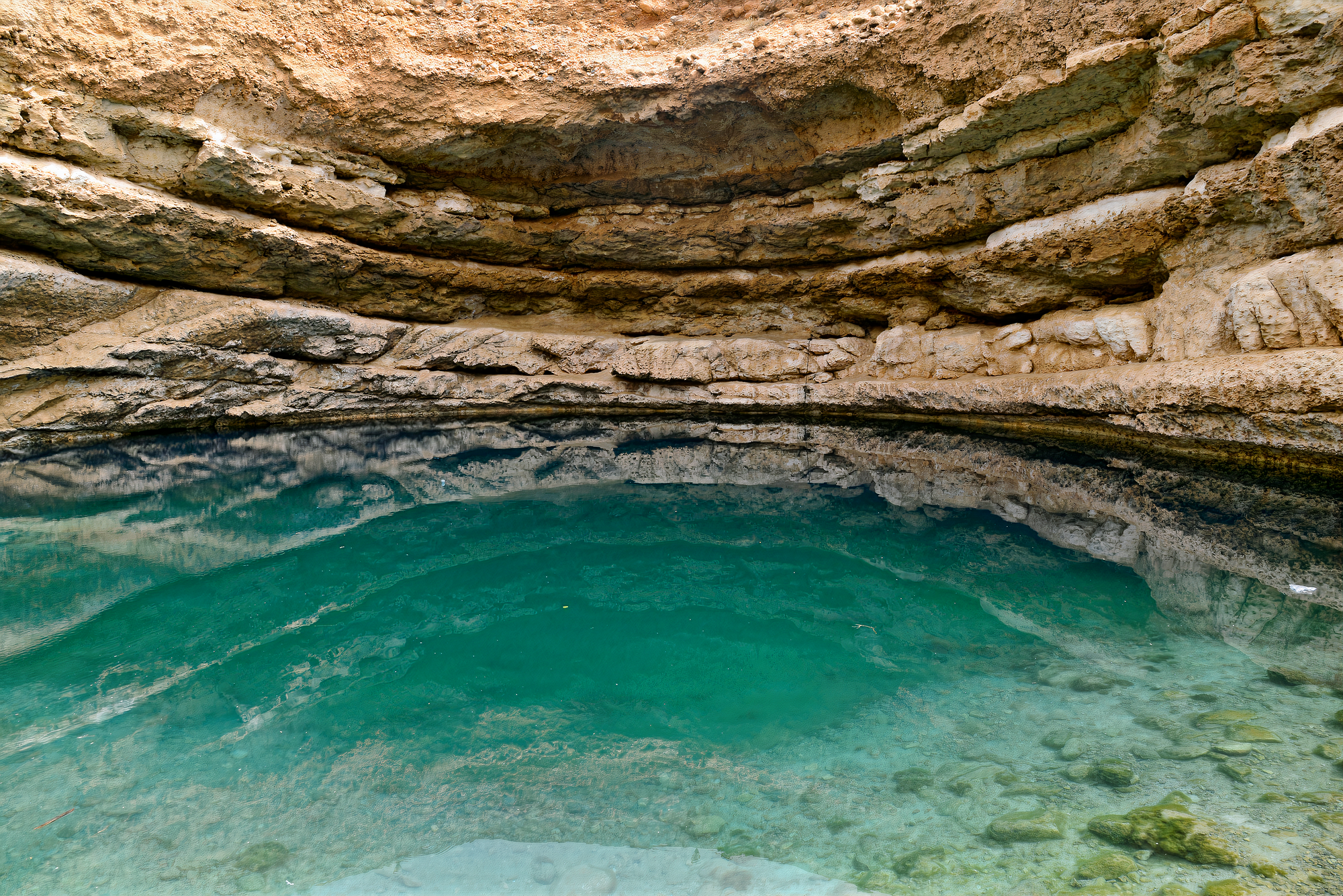 Stunning view from inside Bimmah Sinkhole, revealing the clear turquoise waters, rugged rock formations, and natural beauty.