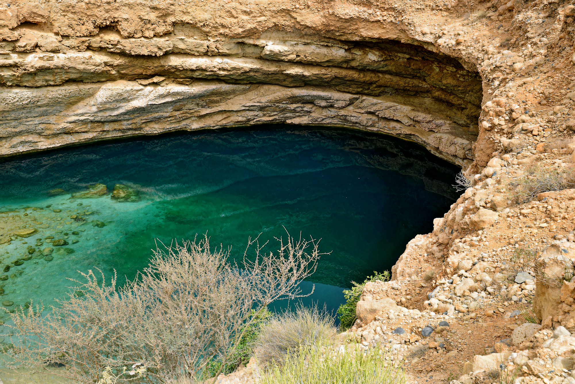 Stunning view from inside Bimmah Sinkhole, revealing the clear turquoise waters, rugged rock formations, and natural beauty.