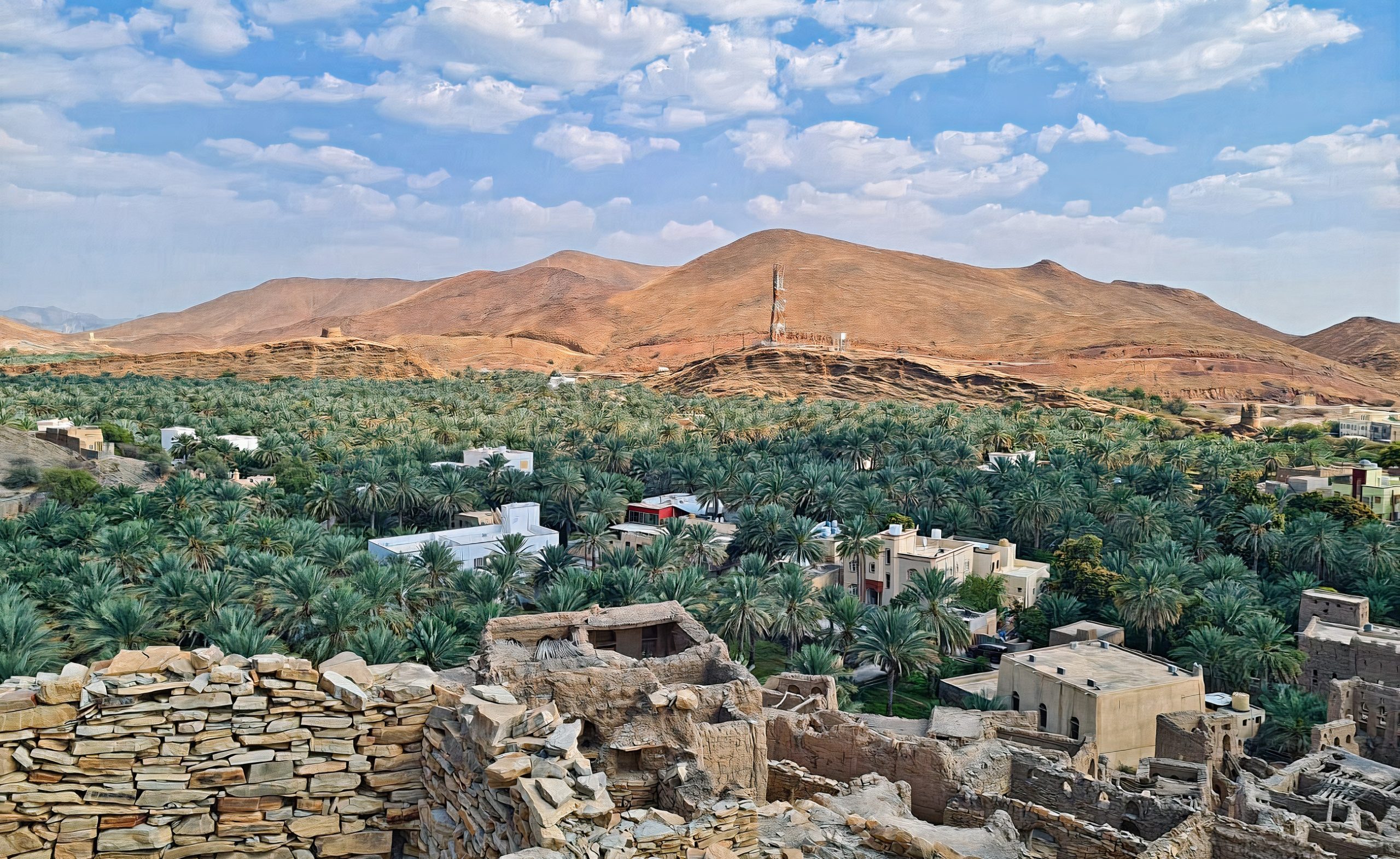 Serene view of Birkat Al Mouz, Oman, showcasing the charm of this ancient village nestled at the foot of Jebel Akhdar. Amongst lush date and banana plantations, mud-brick structures stand as a testament to Oman's timeless beauty and heritage.
