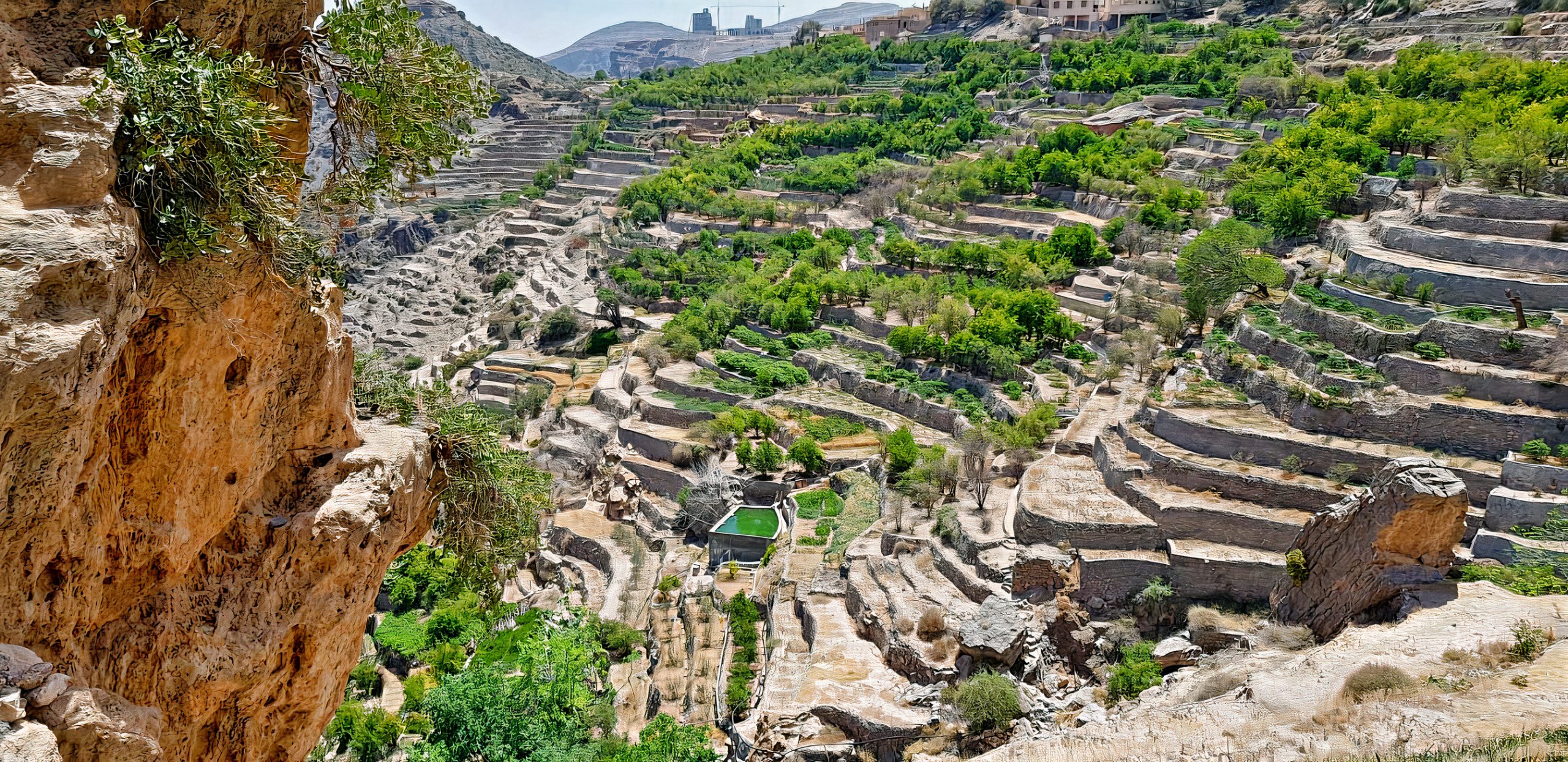 Breathtaking view of Jebel Akhdar, Oman's renowned Green Mountain, adorned with vibrant fruit plantations and rose gardens. The lush landscape, bathed in sunlight and shadow, offers a serene ambiance and showcases the diverse natural beauty of Oman.