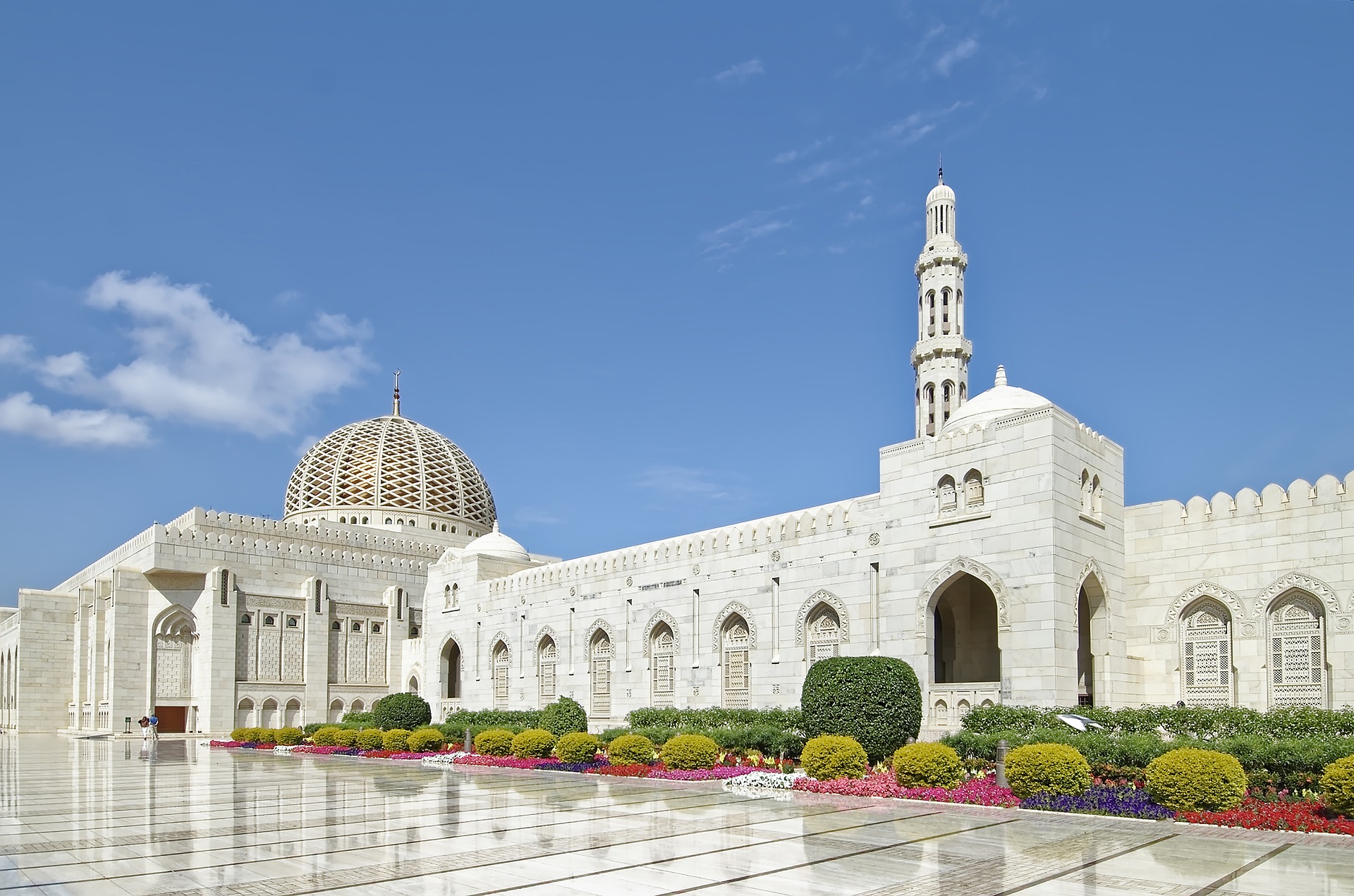 The impressive interior of the Sultan Qaboos Grand Mosque, featuring intricate Islamic art, a large chandelier, and a beautifully crafted carpet.