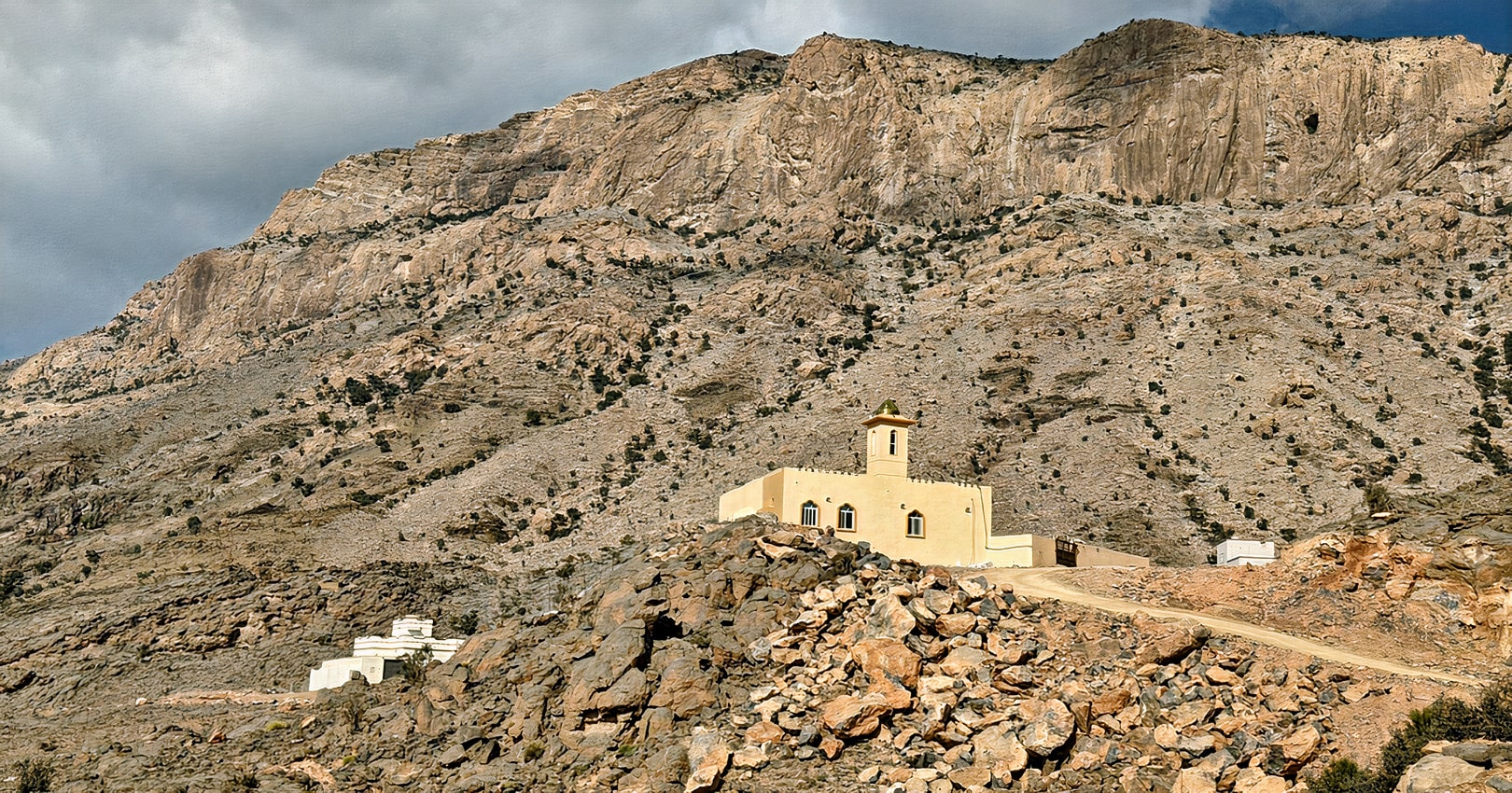 A traditional stone house along the W6 Balcony Trail is nestled against the rugged mountain backdrop of Jebel Shams.